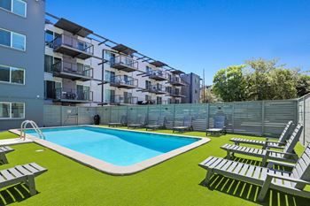 an image of an apartment complex with a swimming pool and lounge chairs